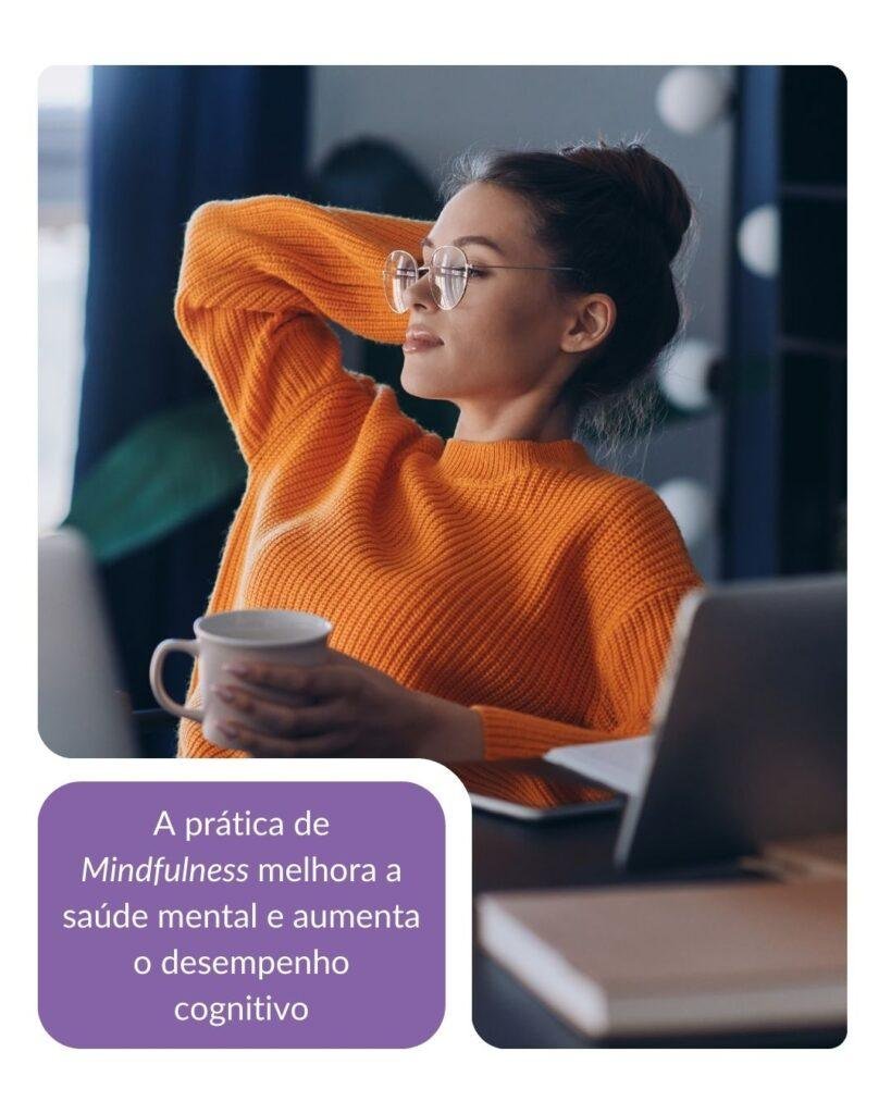 Mulher usando óculos e suéter laranja, segurando uma xícara enquanto olha pensativa para o lado, com o braço apoiado atrás da cabeça. Ao fundo, um ambiente de trabalho com laptop e detalhes desfocados. Uma mensagem em um fundo roxo diz: 'A prática de Mindfulness melhora a saúde mental e aumenta o desempenho cognitivo'