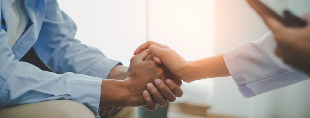 Um profissional de saúde mental segurando a mão do colaborador